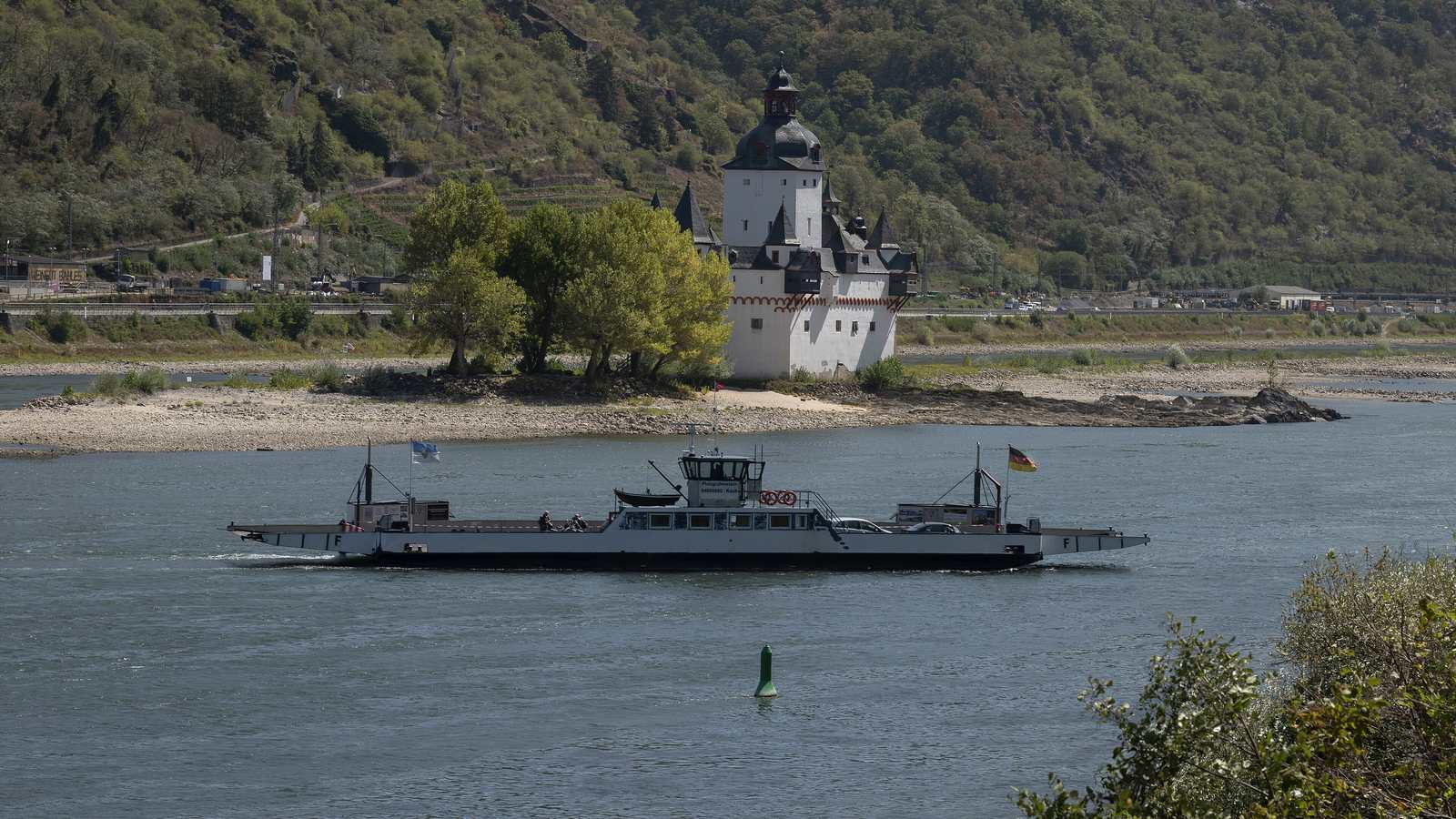 Die Kauber Rheinfähre Pfalzgrafenstein vor der Burg Pfalzgrafenstein, deren Insel bei Niedrigwasser als breite Kiesbank aus dem Rhein ragt